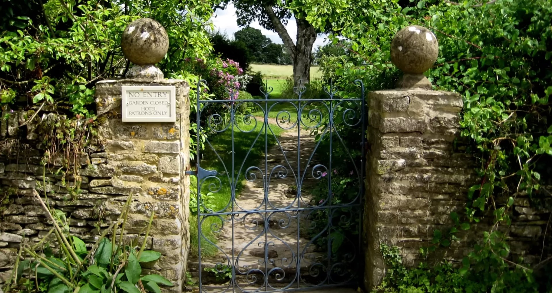 Elegant stone garden entrance with ornate gate and mature landscaping