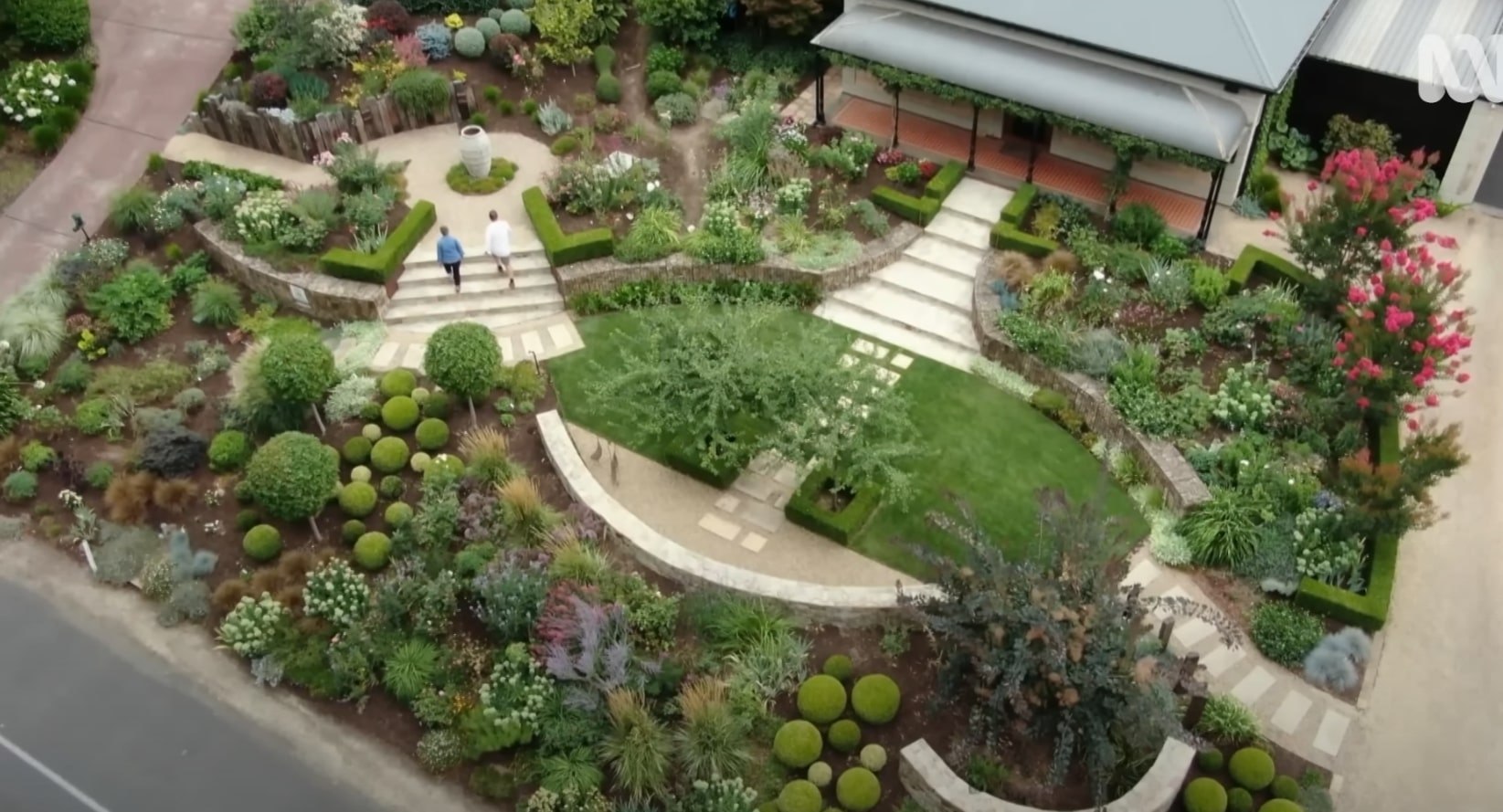 Aerial view of stunning circular garden design with curved pathways, geometric lawn patterns, and diverse plantings